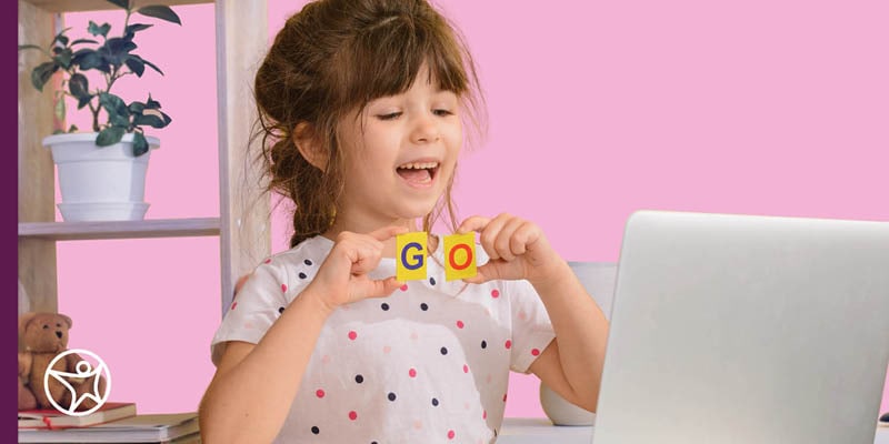 Male child student laying down on the floor reading a book in front of books shelves