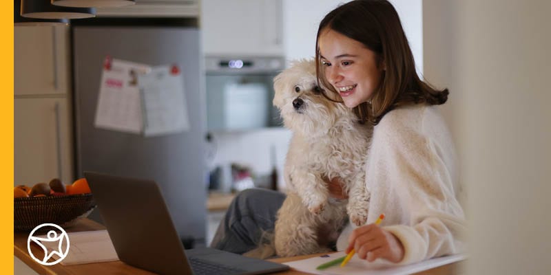 A middle school student holding her dog while writing