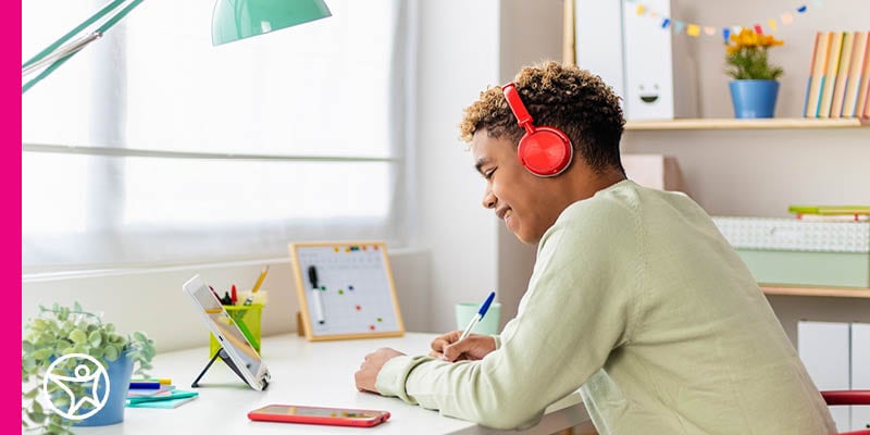 A high school student in a tan shirt listens to an online lesson from Connections Academy.