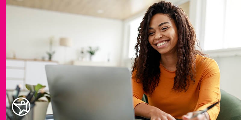 A high school student in an orange shirt listens to an online lesson from Connections Academy.