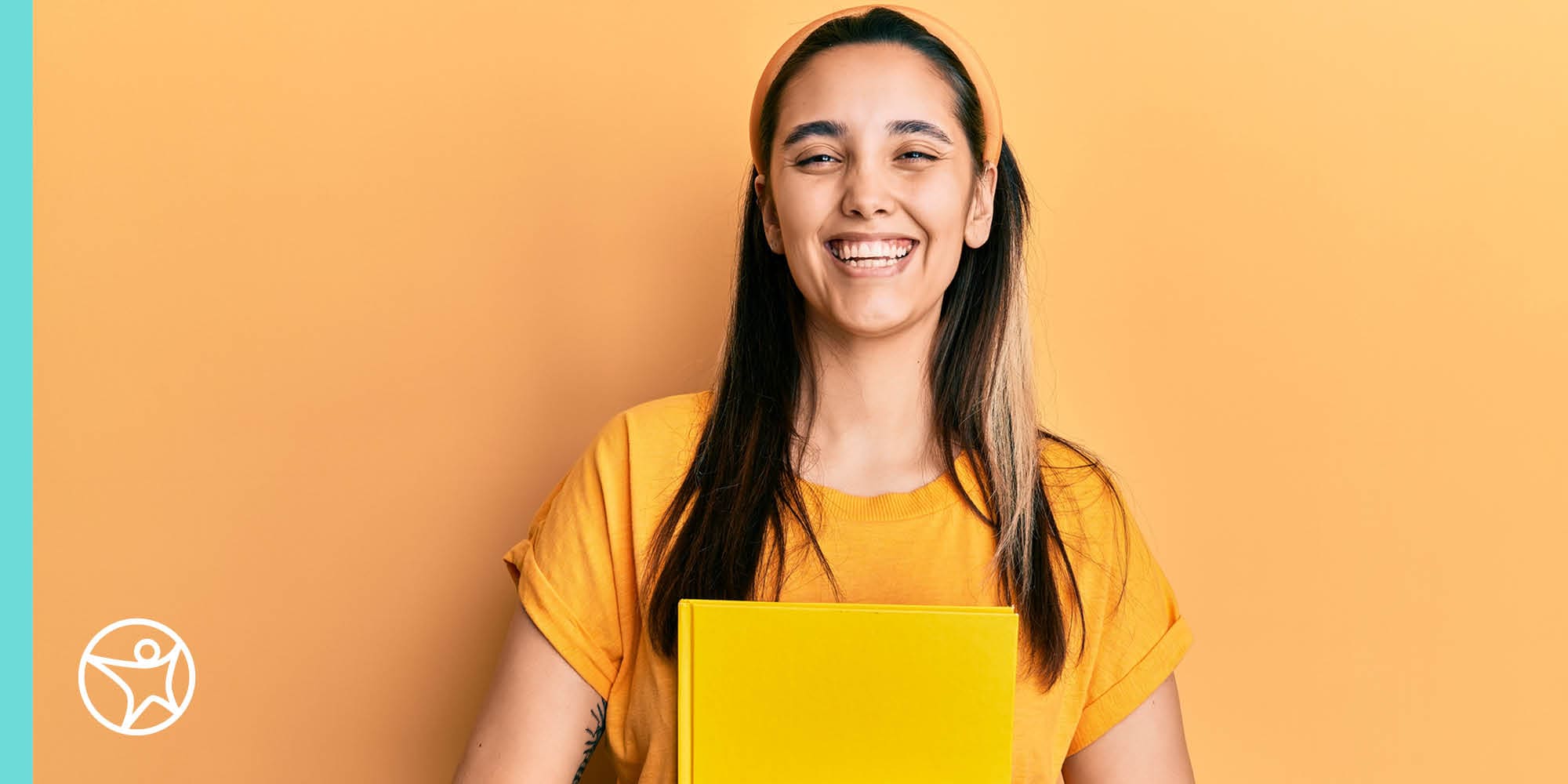 A high school student smiling while holding a notebook