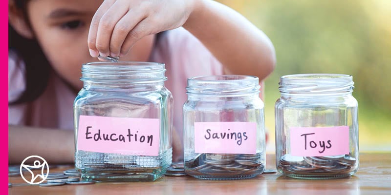 A young girl is placing a coin into an education jar