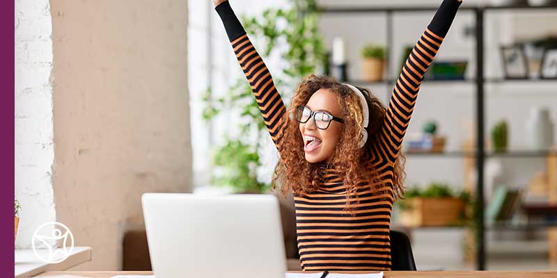 A student in an orange and black striped shirt celebrating in her success in online school and career development at Connections Academy.