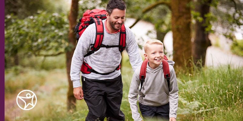 A father and son hiking the woods with red backpacks