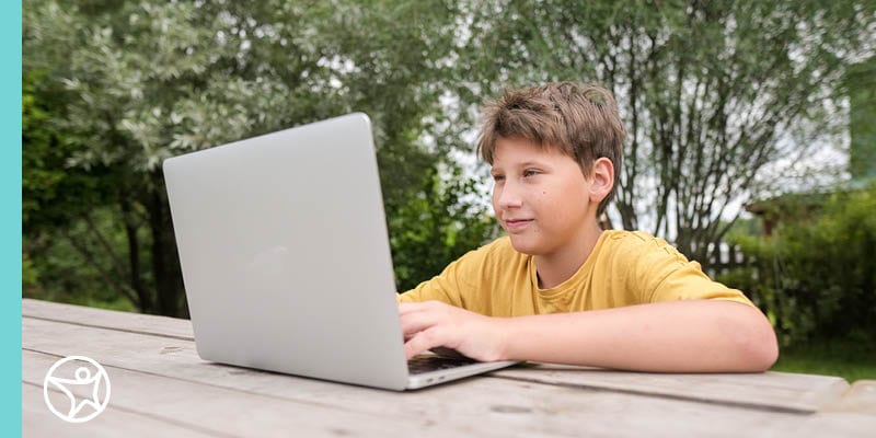 Online school student sitting outside with their laptop