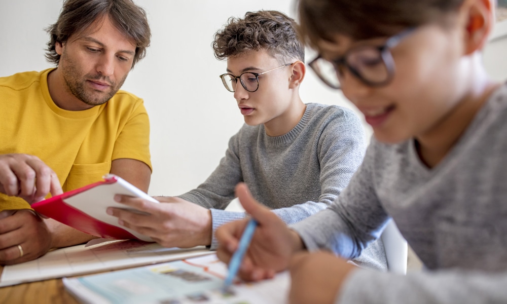 Father helping his two children with homework