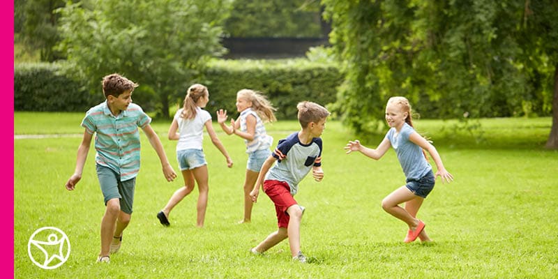 An image of several children running and playing in a field during the summer break.