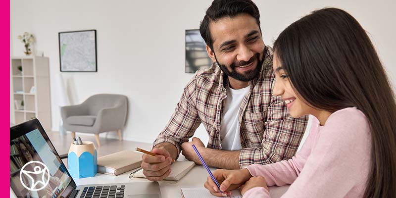 Student studying in a pink sweater looking at her laptop while taking online class at Connections Academy while working with her father/learning coach.