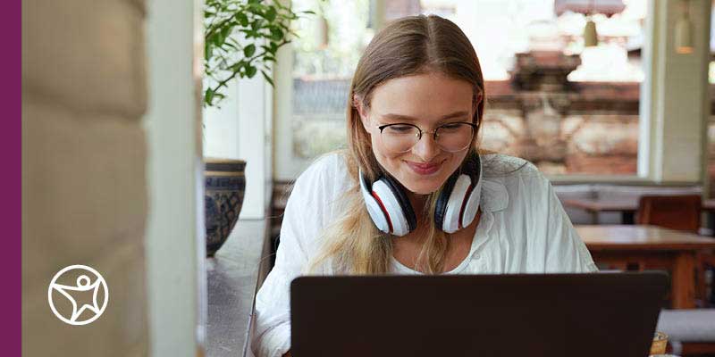 Image of a student wearing a white shirt working on her laptop while taking online career classes at Connections Academy.