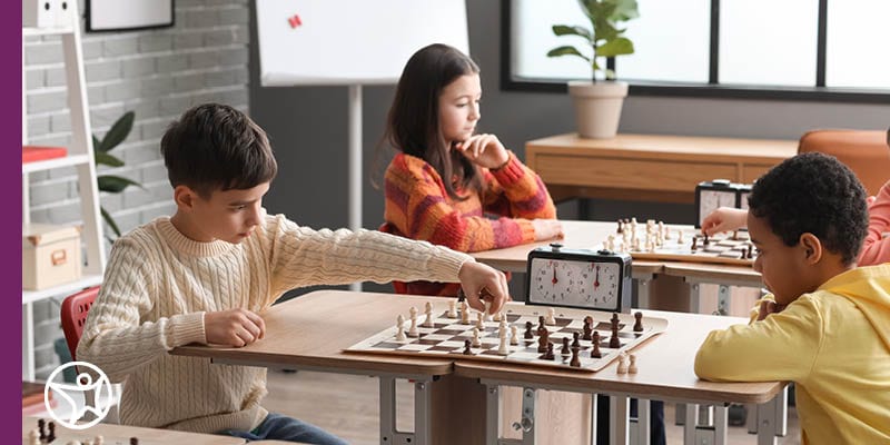 Connections Academy online middle school students sitting together at a table playing chess during a Connections Academy club event.
