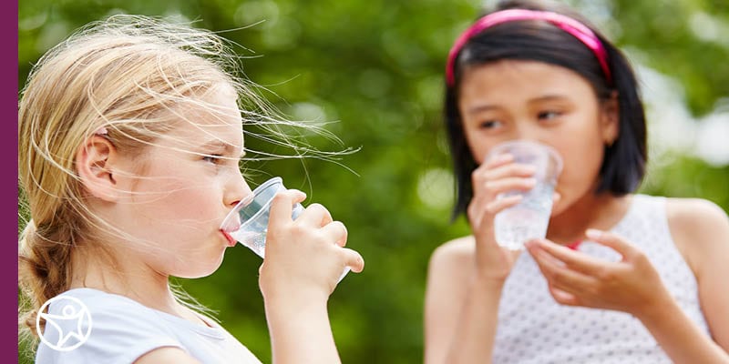 Image of two young female students who are both drinking a glass of water.