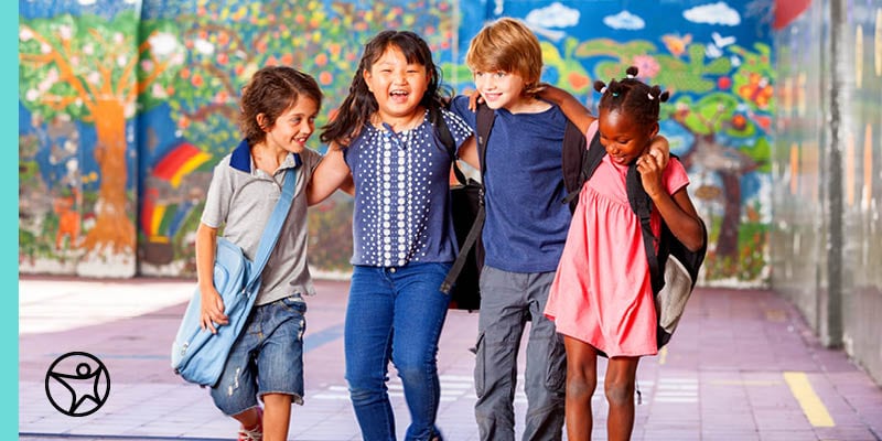 A group of diverse children walking happily down the street.