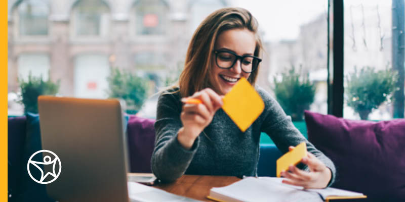 A young high school student in a green sweater is sitting at her desk planning her high school graduation from Connections Academy online school.