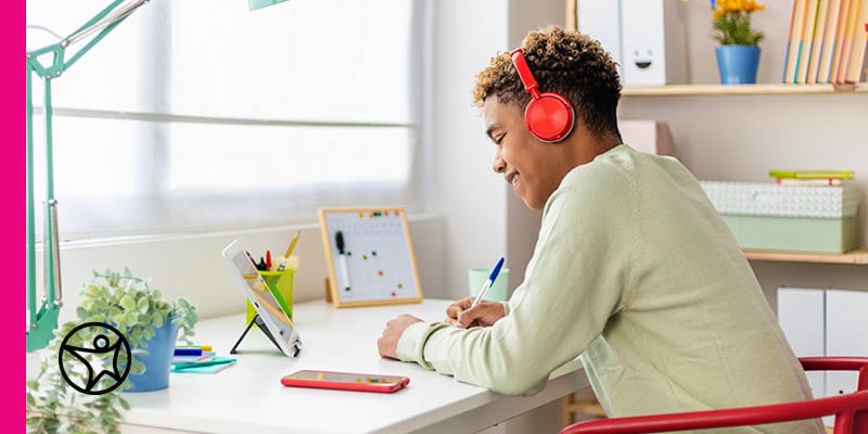 A young teen boy with red headphones is working on an online assignment for Connections Acacdemy.