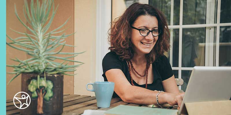 A smiling teacher giving assistance to an online special education class.