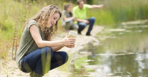 A student enjoying homeschool nature activities near a lake.