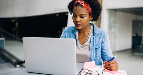 An online school student using time management skills to organize her tasks into a schedule. 