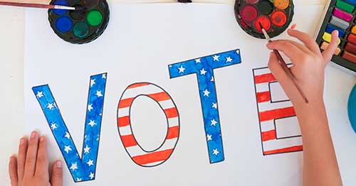 A child creating a sign that says Vote. 