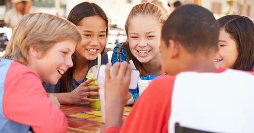 A group of online school friends gathered around a cell phone. 