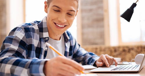 An online school high school freshman taking notes.
