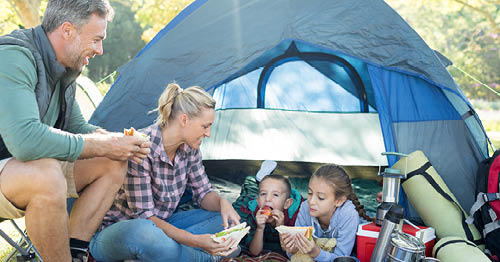 A family spending their national outdoor play days camping in a tent and having a picnic.