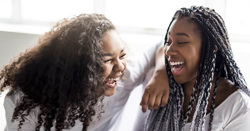 Two teenagers openly expressing their teenage emotions by laughing. 