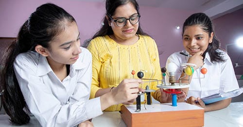 Learning Coach in a yellow sweater with her two daughters working on an Connections Academy online assignment on the solar system. 