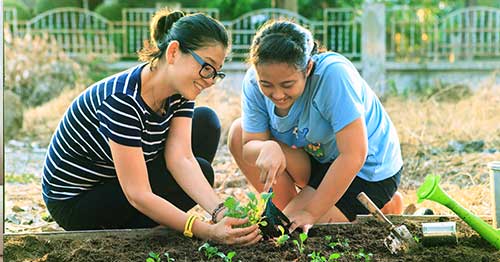Young students in a garden planting vegetables.