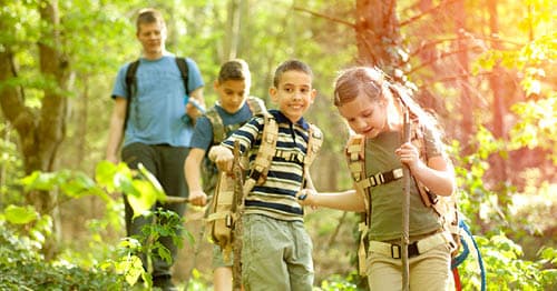 A family hiking in the woods as a fun summer learning activity. 