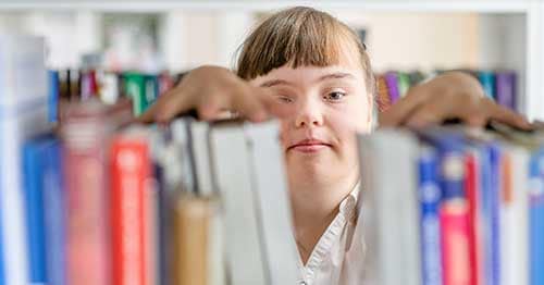 A student looking through books as part of her special education online.