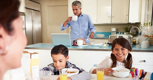 A family eats breakfast as part of their morning routine before school.