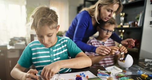 A working parent helping her children with their virtual school assignments.