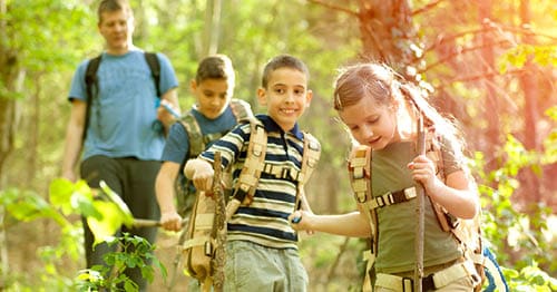 A group of kids and a parent hiking.