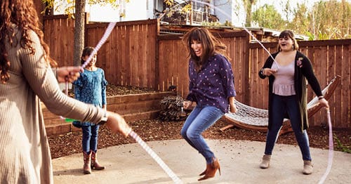 A group of teens enjoying summer activities by playing with a jump rope. 