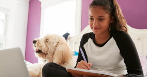 An online school student doing schoolwork with her pet showing the benefits of kids learning with their pets.