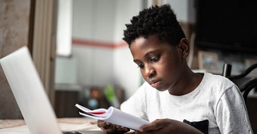 An online school student reading a book while in online school.   