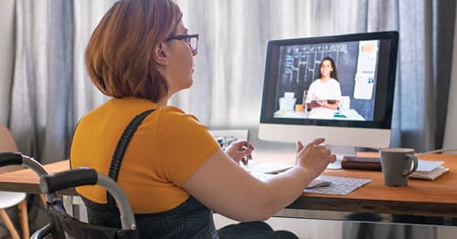 An online school student, who uses a wheelchair, speaking with her teacher through a video chat.  