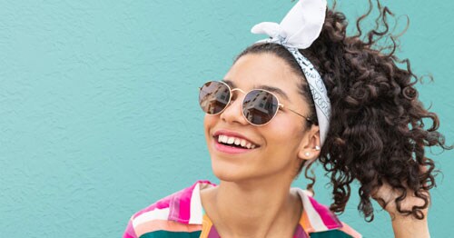 Young young smiling in a colorful shirt and a white bandana hair tie. 