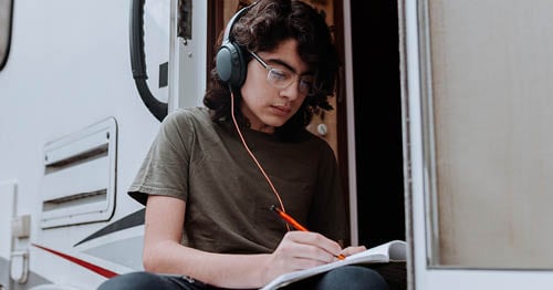 An online school student journaling in a notebook as part of scheduled screen-free time. 