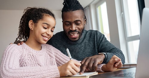 Young female student with her father Learning Coach working on an online assignment. 