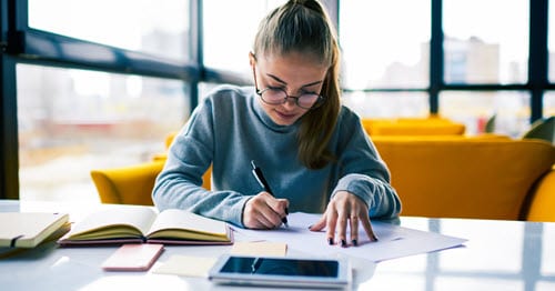 An online student writing down the goals she wants to accomplish after high school graduation.