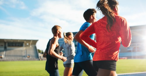 A group of high-school students running track. 