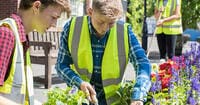 A pair of online school students volunteering in their community garden as part of a learning pod activity.