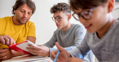 A father helping his two online school students with their assignments. 