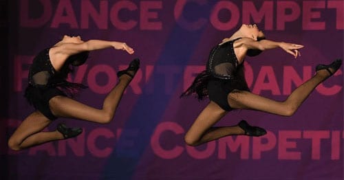Two young girls dance on a stage in black leotards.