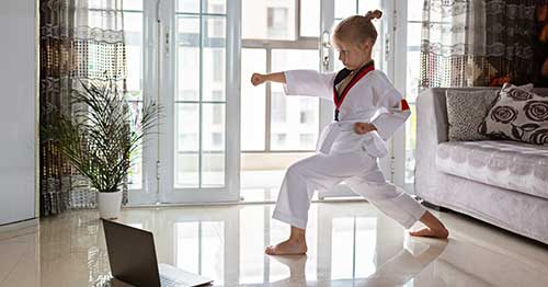 A child practicing martial arts in an online class. 