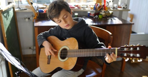 Image of a young student playing the guitar