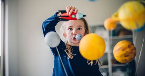 Image of a young female student making a model of the solar system. 