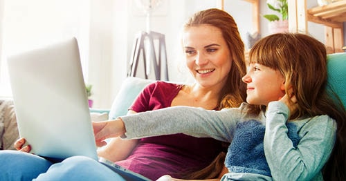 A Learning Coach using a laptop helps her elementary school student become more motivated to learn.