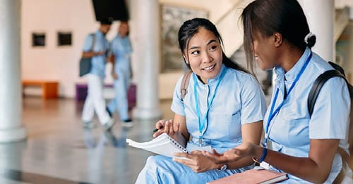 Two students in blue uniforms conversing together about a Health Science CTE course they are taking through Connections Academy.    